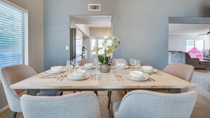 Une salle à manger avec une table en marbre dressée pour six personnes, des chaises gris clair et un arrangement floral central.