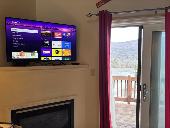 A television displaying a Roku TV interface with various streaming options and a fireplace below. - Ski in/out 2b2b at Hunter! (Lanesville)