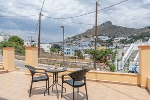 A terrace with two chairs and a table, overlooking a hillside town with buildings and a prominent hill. - Apartment 'One Bedroom' with Mountain View, Wi-Fi and Air Conditioning (Leros)