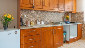A kitchen with wooden cabinets, a tiled backsplash, a refrigerator, and a sink.