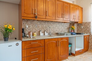 Una cocina con armarios de madera, salpicadero de azulejos, un refrigerador y un lavamanos.