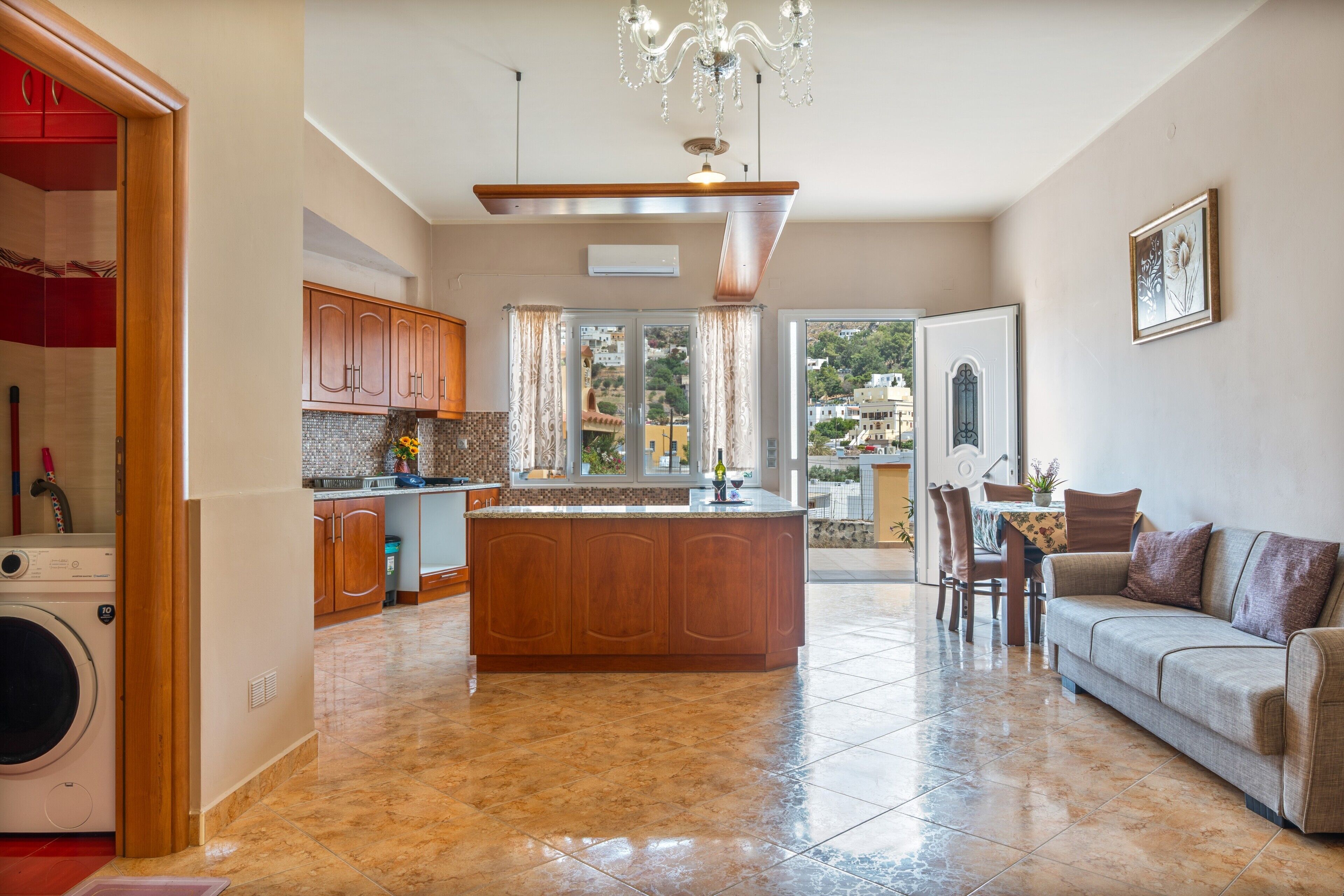 A spacious kitchen with a central island, wooden cabinets, and a chandelier.