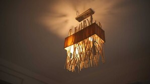 Eine Deckenleuchte mit Holzrahmen und einem hängenden, blattformigen Design.