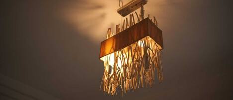 A ceiling-mounted light fixture with a wooden frame and a hanging, leaf-like design.