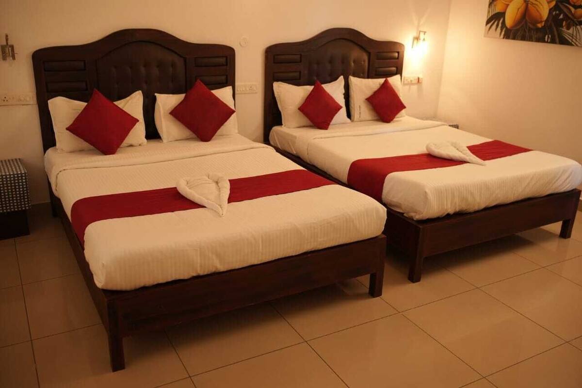 Two identical twin beds with wooden headboards, white linens, and red pillows.