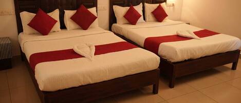 Dos camas gemelas idénticas con cabeceras de madera, sábanas blancas y almohadas rojas.
