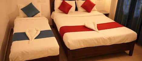 Dos camas individuales con cabeceros de madera, ropa de cama blanca y almohadas rojas y azules.