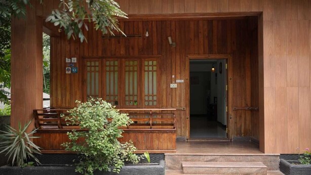 Ein Gebäude aus Holz mit traditionellem Design, vor der Tür eine hölzerne Bank und eine Tür zum Eingang.