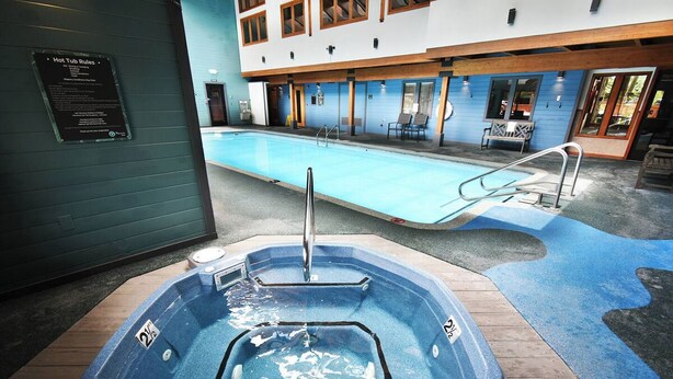 A hot tub with a pool in the background, a sign with hot tub rules, and a wooden deck area. - *NEW* Uncover Frisco's winning views w/resort-style amenities; total package! (Frisco)