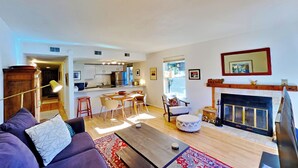 A modern living room with a sofa, coffee table, and fireplace. There is a kitchen in the background with a dining area. - *NEW* Uncover Frisco's winning views w/resort-style amenities; total package! (Frisco)