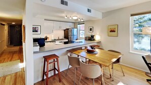 A modern kitchen with white cabinets, a stainless steel refrigerator, and a wooden dining table with four chairs. - *NEW* Uncover Frisco's winning views w/resort-style amenities; total package! (Frisco)