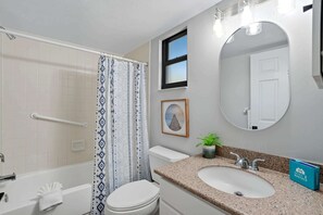 A bathroom with a bathtub, toilet, sink, and shower curtain.