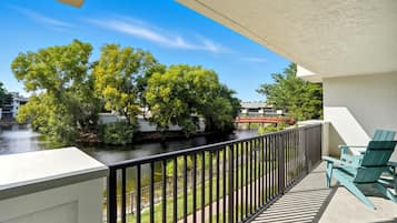 A balcony with a view of a river, greenery, and a red bridge.