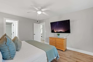 A bedroom with a bed, pillows, a dresser, a ceiling fan, and a TV on the wall. - I-252 Updated With Views, Pool, & Near Beach! (Naples)