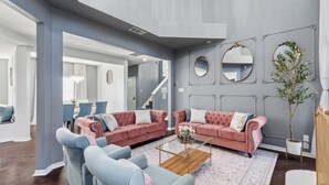 A spacious living room with two pink sofas, a coffee table, and a large mirror on the wall. - French-Style 5-BD w/ Pool, Playground, Cinema (Lewisville)