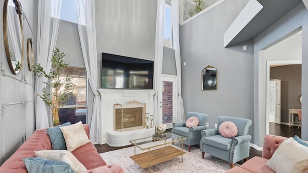 A modern living room with a fireplace, plush seating, and a large window. - French-Style 5-BD w/ Pool, Playground, Cinema (Lewisville)