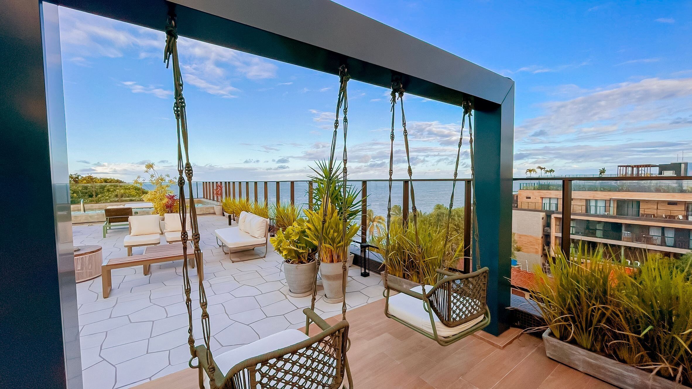 Un balcón con vistas al mar, mobiliario exterior y plantas en macetas.
