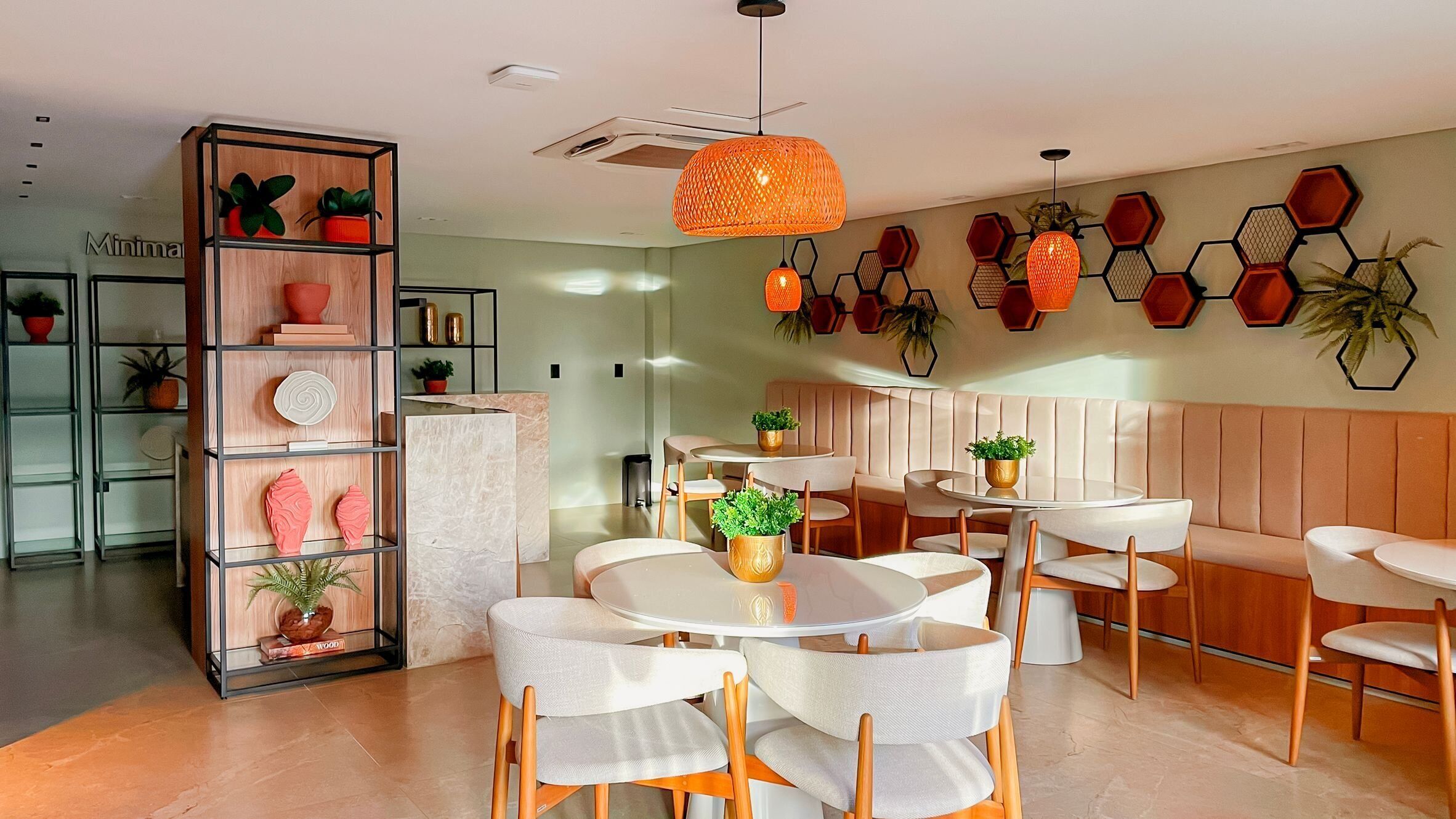 Un interior moderno con mesas y sillas redondas, una estantería de madera y decoraciones hexagonales en la pared.