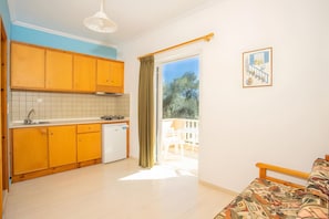 Una cocina compacta con muebles de madera, encimera blanca y un refrigerador pequeño.