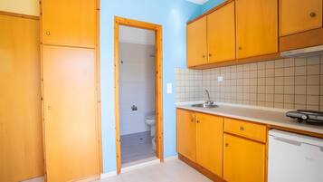 A kitchen with wooden cabinets, a white countertop, and a dishwasher.
