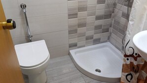 A bathroom with a toilet, a shower, and a sink.