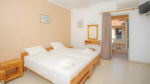 A bedroom with a double bed, bedside tables, a mirror, and an air conditioning unit.