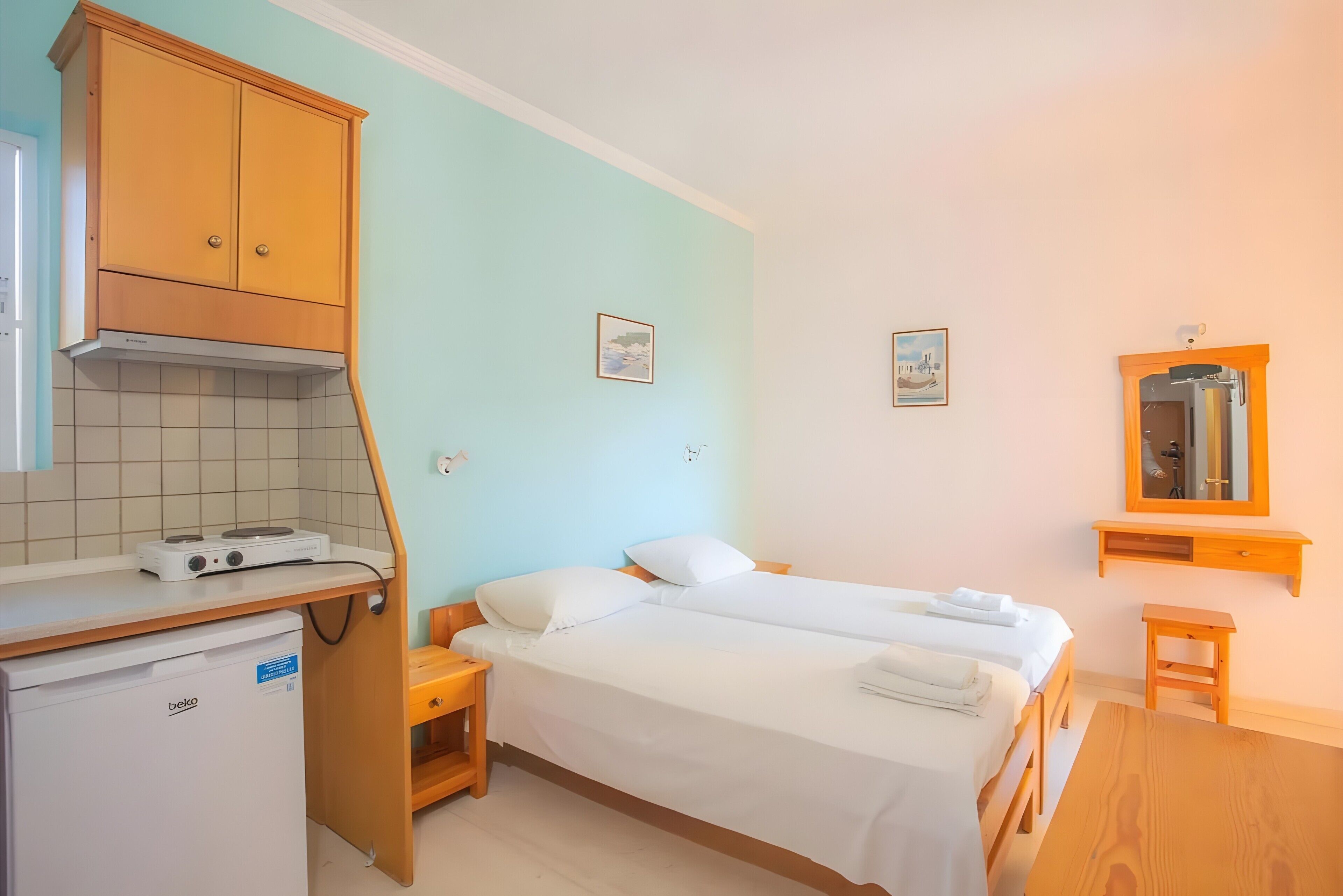 Une chambre à coucher avec un lit, une table de chevet et un petit tabouret en bois.