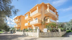 Un immeuble à plusieurs étages doté de balcons, d’un mur en pierre et surplombant un ciel dégagé.