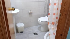 A bathroom with a toilet, a small trash bin, a sink, and a shower curtain. - Apartment 'Nidri View B4' with Mountain View, Wi-Fi and Air Conditioning (Nydri)