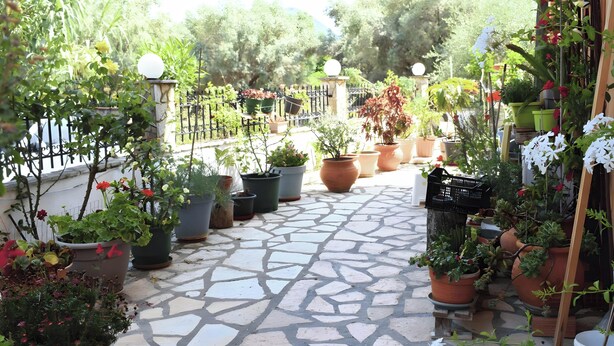 A stone-paved patio with potted plants and a metal fence. - Apartment 'Nidri View B4' with Mountain View, Wi-Fi and Air Conditioning (Nydri)