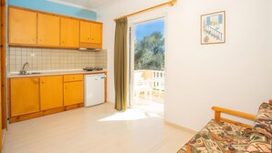 A compact kitchen with wooden cabinets, a white refrigerator, and a dining area with a table and chairs.