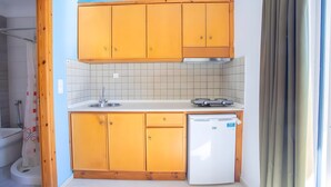 A compact kitchen with wooden cabinets, a white sink, and a built-in dishwasher.