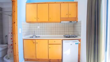 Een kleine keuken met houten kastjes, een witte spoelbak en een ingebouwde vaatwasser.