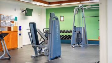 Ein Fitnessstudio mit Kraftgeräten, Hanteln und einer Rezeption mit Handtüchern.