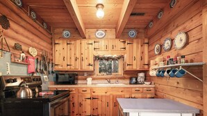 Cuina d'una cabana de fusta amb forn, microones, rentapeus i taula.
