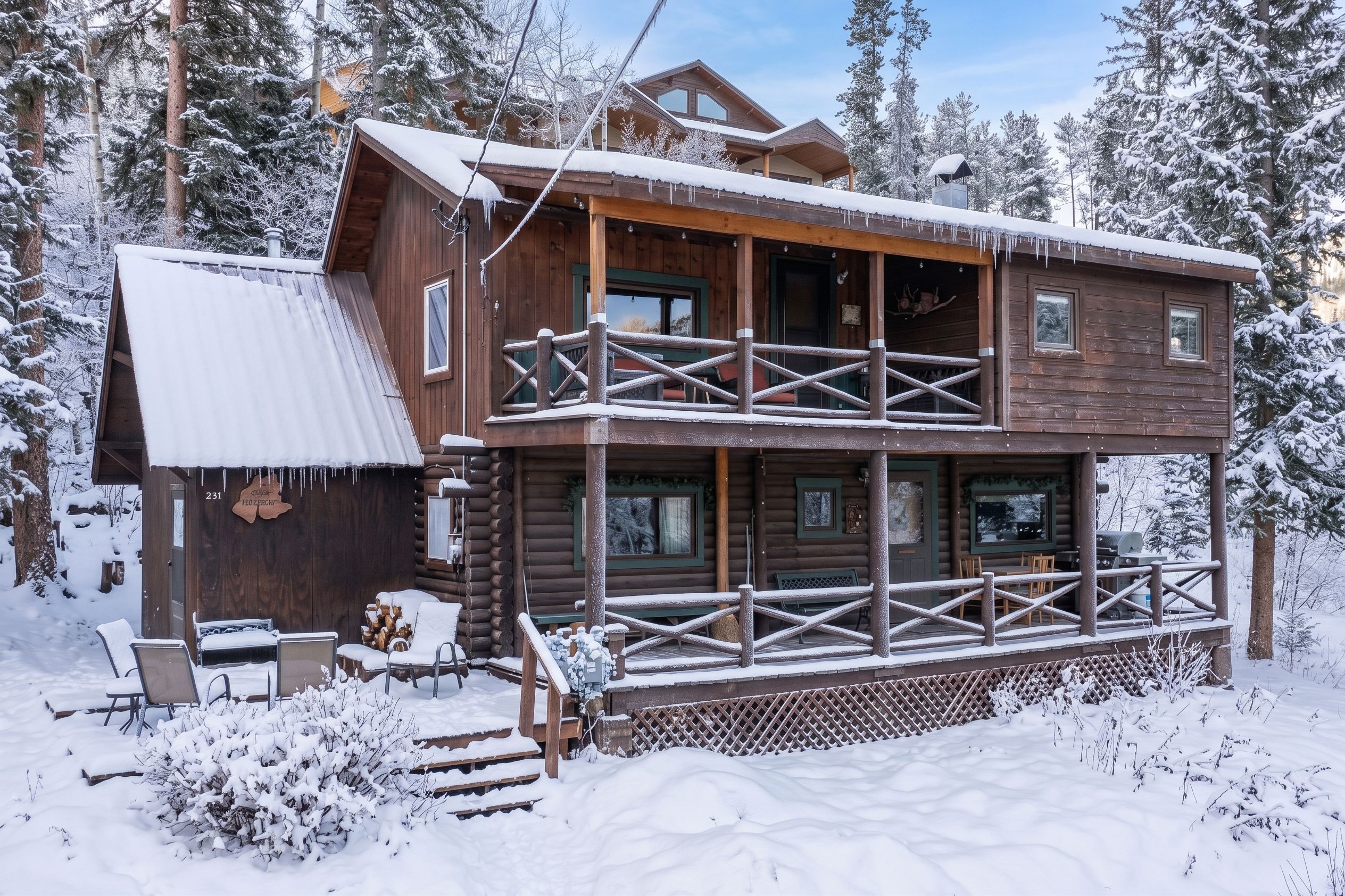Une cabane en rondins à deux étages, dotée d’un balcon et entourée d’arbres couverts de neige.