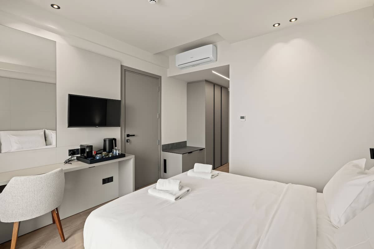 Habitación de hotel moderna con una cama, un escritorio con silla, un televisor de pantalla plana y un equipo de aire acondicionado.