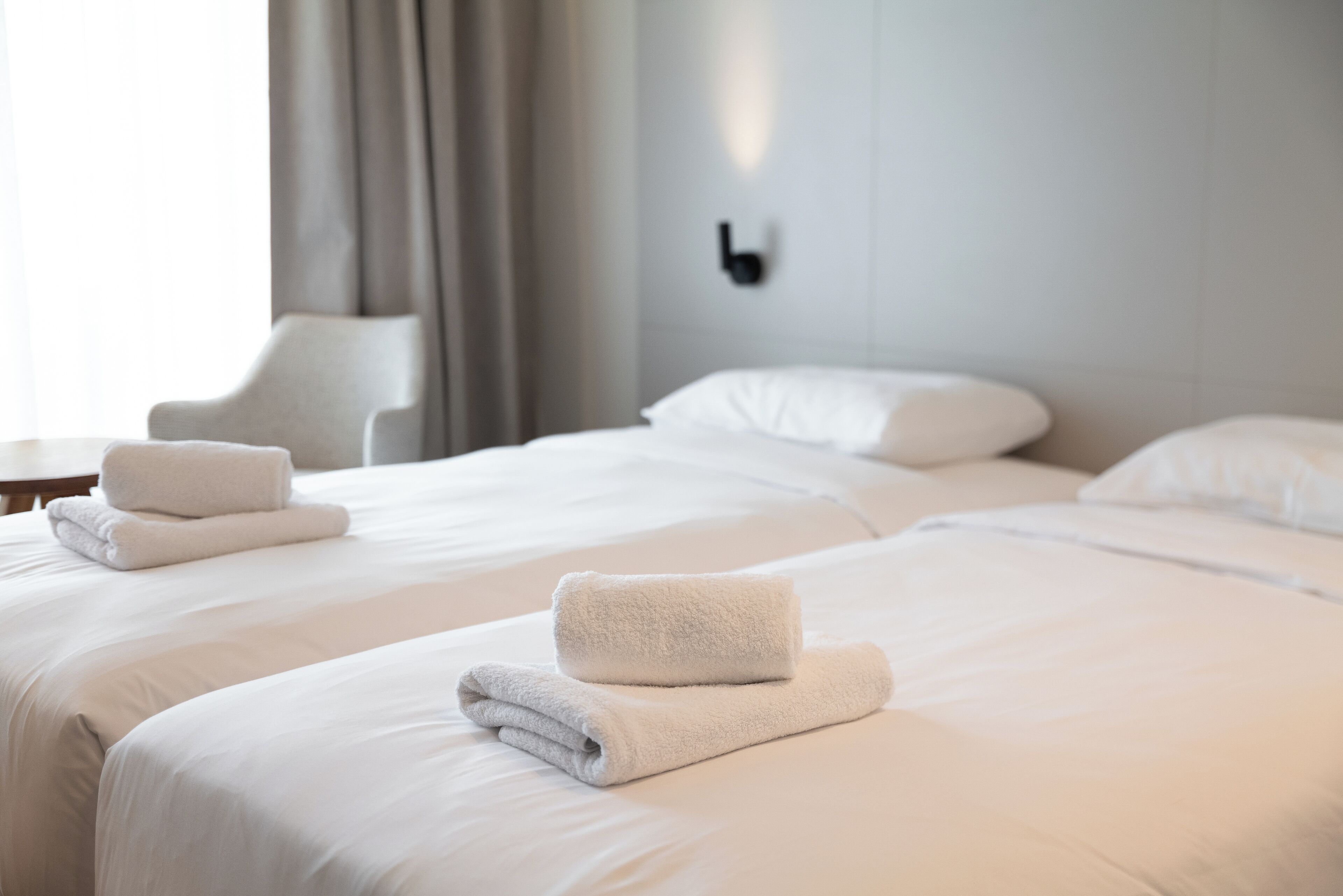 A hotel room with two beds, white linens, and neatly folded towels.
