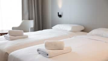 A hotel room with two beds, white linens, and neatly folded towels.