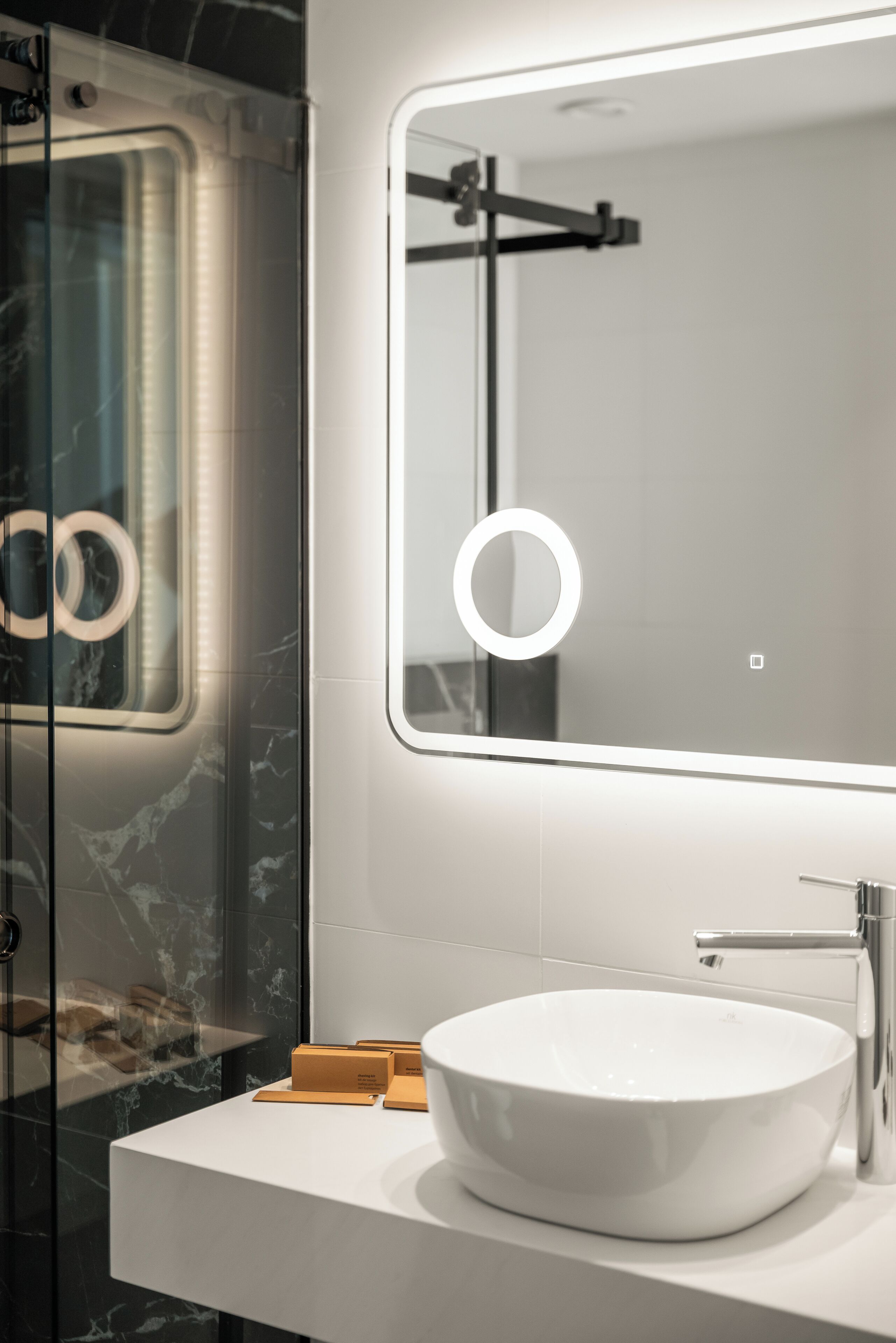 A modern bathroom with a white sink, a large mirror, and a glass shower enclosure.