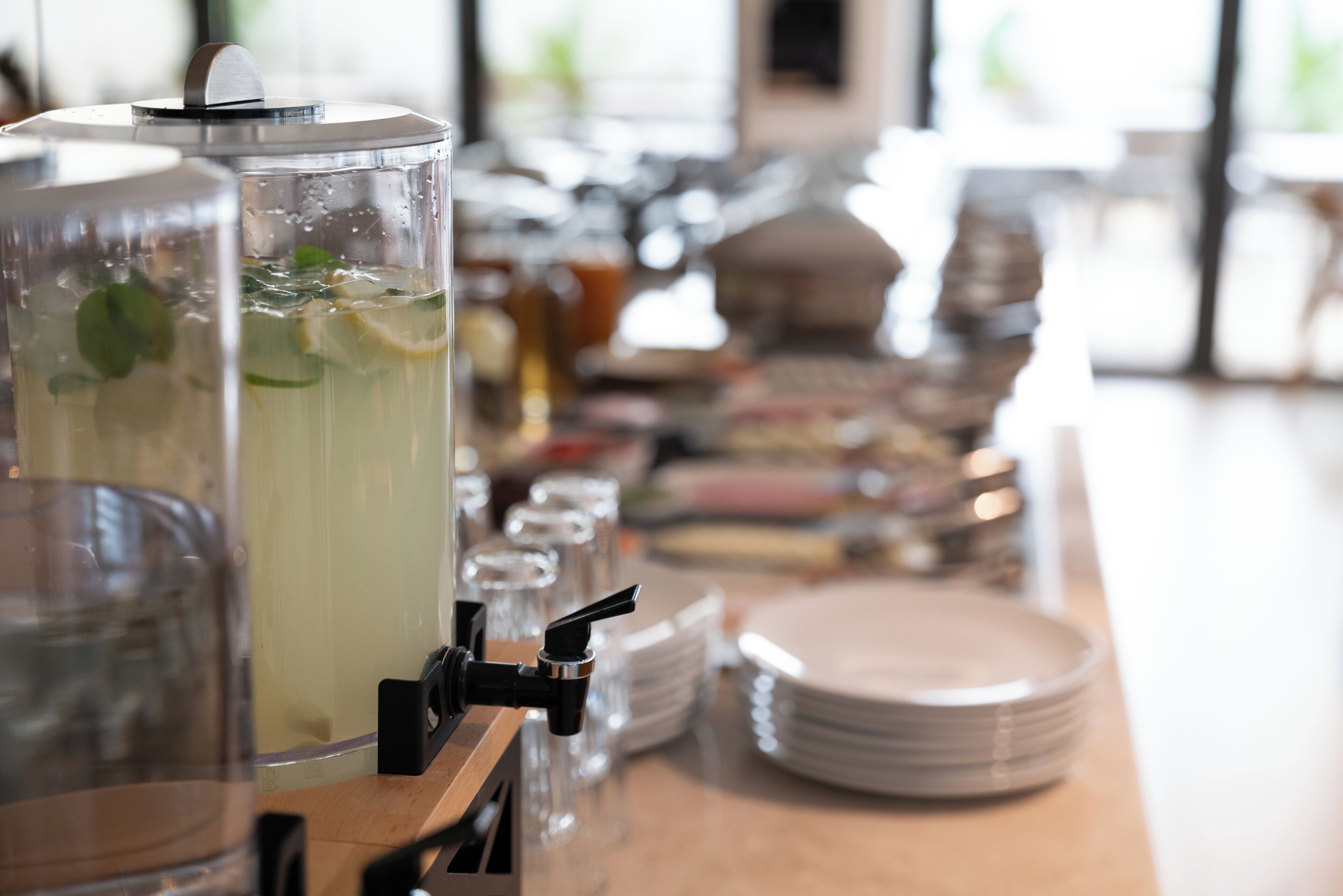 A beverage dispenser with a clear container filled with a drink, mint leaves, and lemon slices.