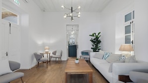 A modern living room with a wooden coffee table, white sofas, and a large plant. - Warner Boutique Hotel (Larnaca)