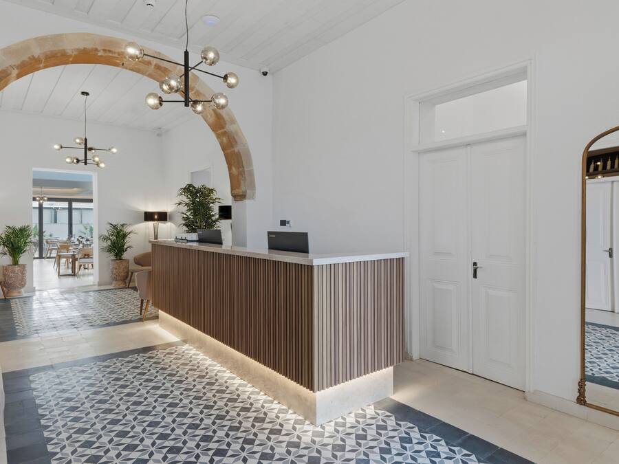 Zona de recepción con un mostrador de madera, piso estampado y un amplio arco.