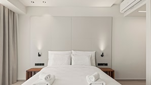 A modern hotel room with a large bed, two bedside tables, and a wall-mounted air conditioner. - Warner Boutique Hotel (Larnaca)