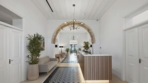 A modern interior with a central archway, a reception desk, a sofa, and a potted plant. - Warner Boutique Hotel (Larnaca)