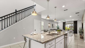A modern kitchen with a granite countertop, stainless steel appliances, and pendant lighting. - Family Fun Villa w Pool, Hot Tub & Game Room (Davenport)