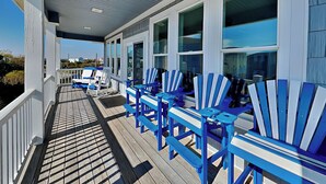 Eine überdachte Veranda mit blauen Adirondack-Stühlen und einer Holzterrasse.