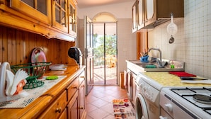 A kitchen with wooden cabinets, a washing machine, a stove, and a sink. - Villa 'Degli Ulivi' with Private Terrace and Air Conditioning (Manduria(c.da Scorcora))
