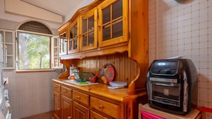 A kitchen with wooden cabinets, a toaster oven, and a window with a view of trees. - Villa 'Degli Ulivi' with Private Terrace and Air Conditioning (Manduria(c.da Scorcora))