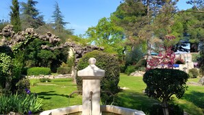 A garden with a fountain, surrounded by trees and shrubs. - Les Berbéris – Gîte in Southern Ardèche (Chandolas)